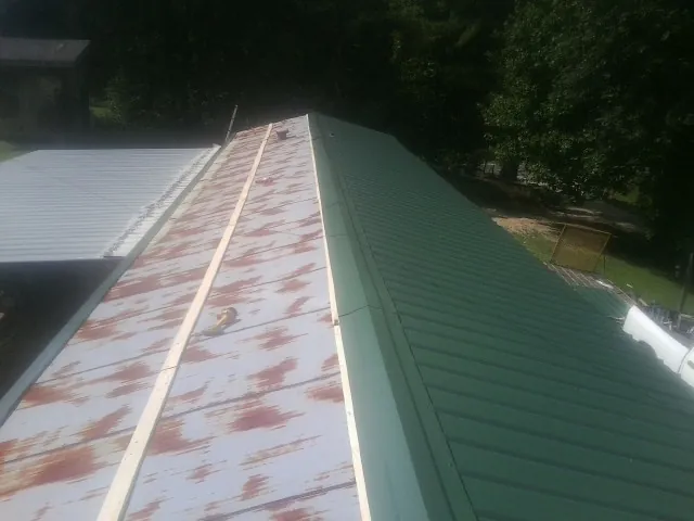 Old rusted panels beside newly installed green metal roofing — Wind Damage Roof Repair by Roofing Brothers in North Chelmsford