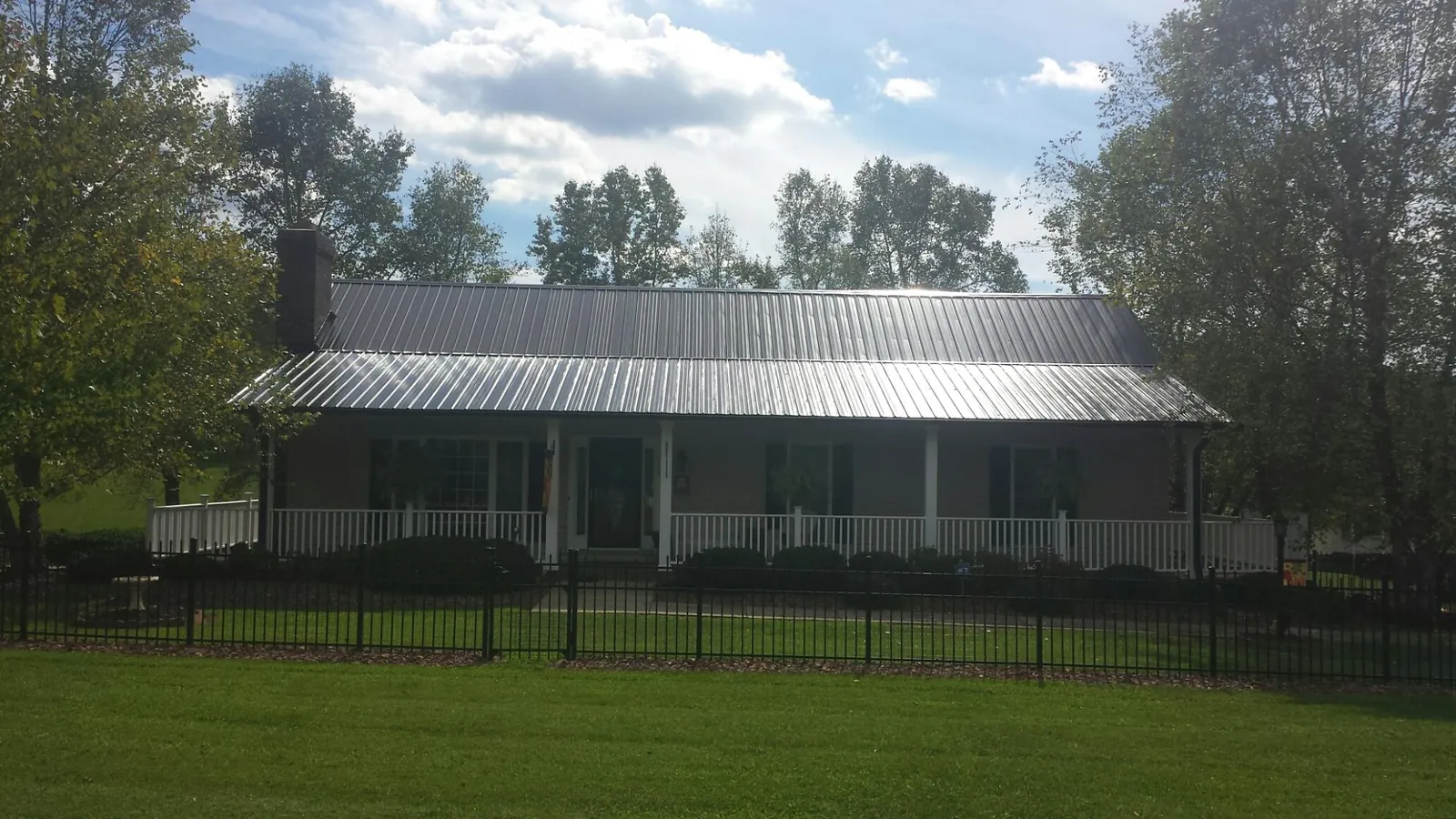 Gray metal roof on a brick ranch with a full width front porch — Gutter Guard Installation work by our crew in North Chelmsford