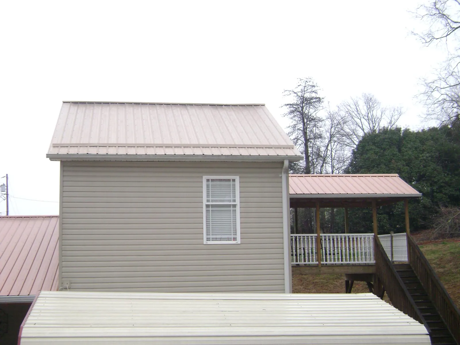 Tan metal roofs on a two story addition and attached porch in North Chelmsford